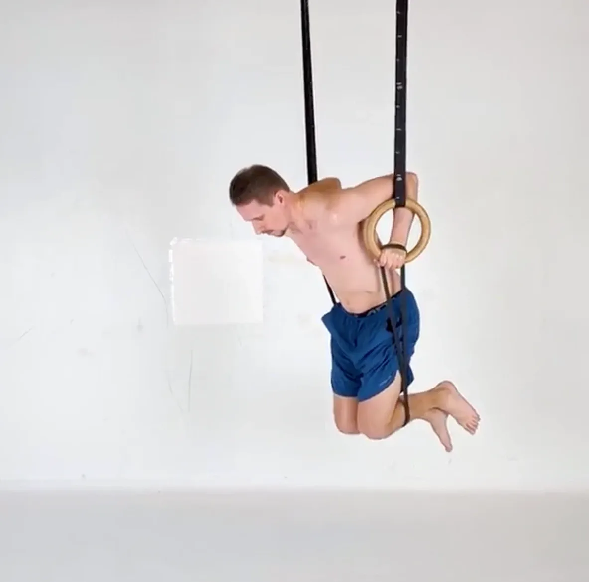 A dip on gymnastic rings with a resistance band looped under the knees